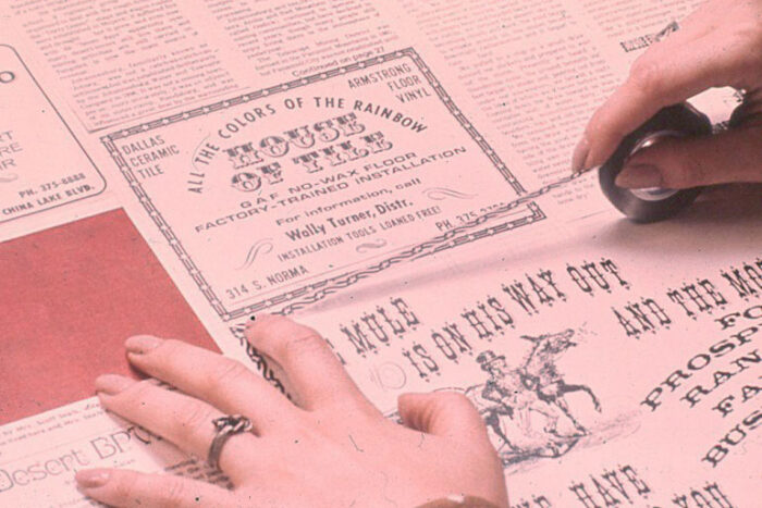 Vintage photo of someone laying out a newspaper by hand.