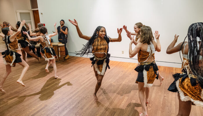 A group of young women dancing in the area outside the Whitsell Auditorium