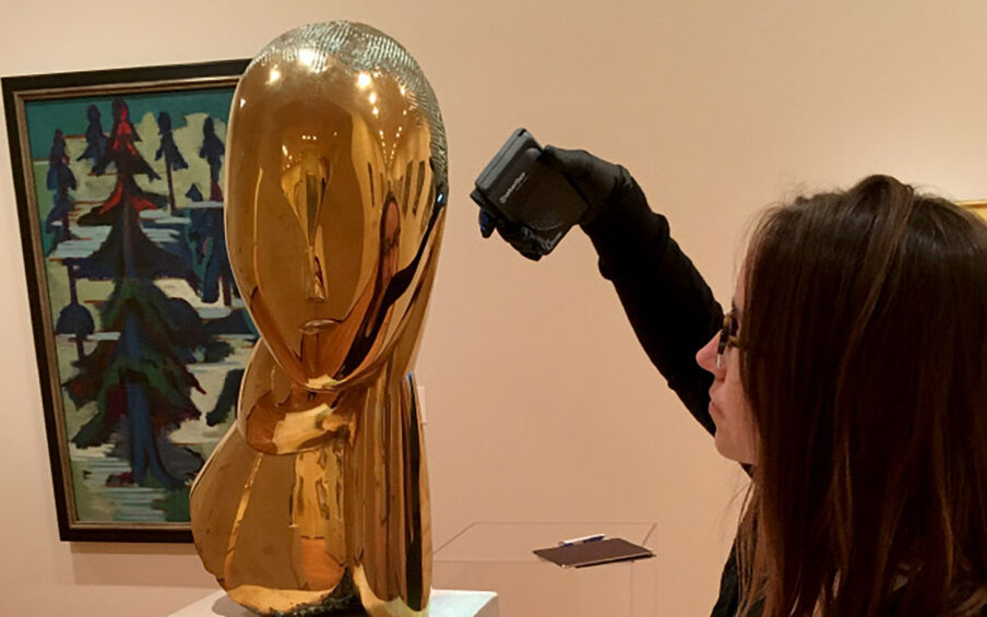 A person examining a bronze sculpture.