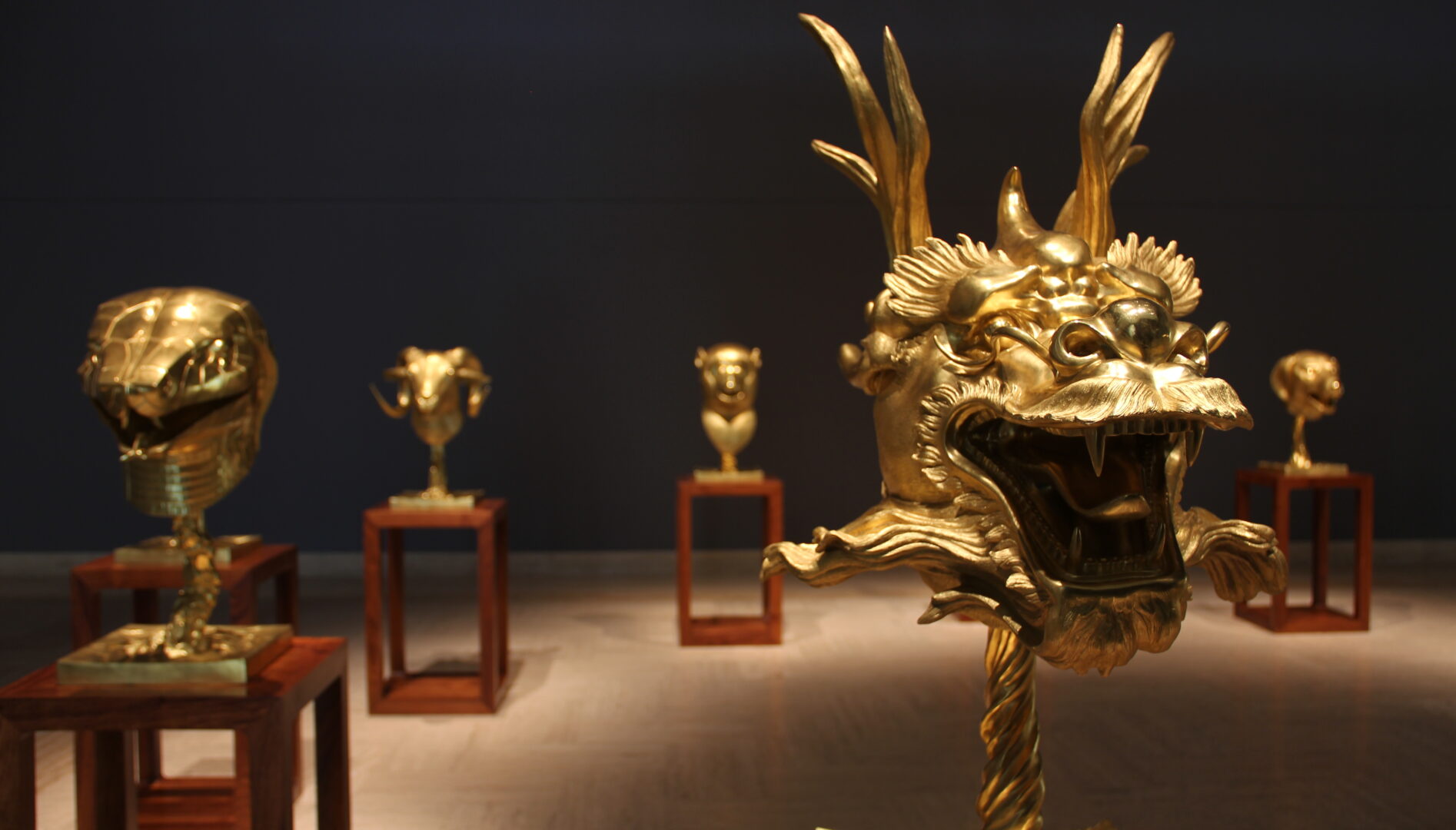 Photograph of a dim gallery with statues of golden heads