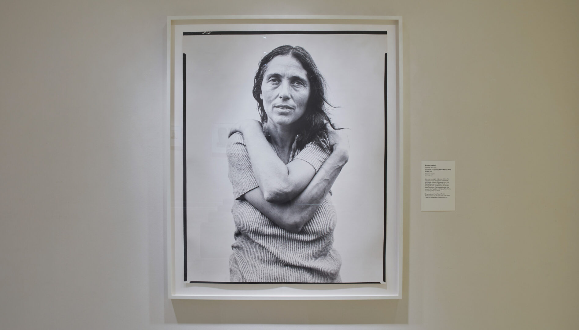 Black and white photograph of a woman with long hair, wrapping her arms around herself