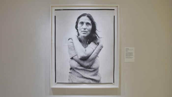Black and white photograph of a woman with long hair, wrapping her arms around herself