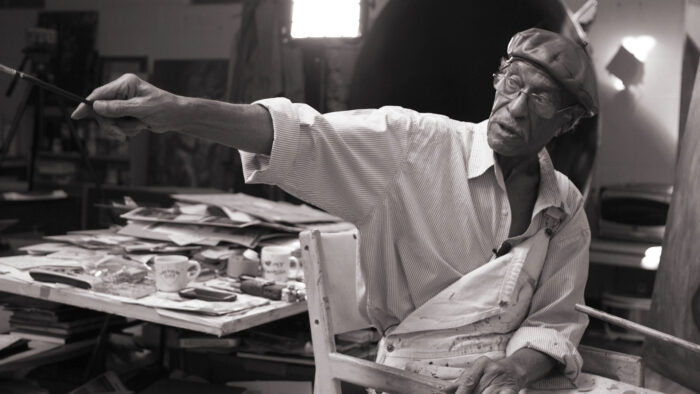 A person sitting at a desk looking and pointing to the right.