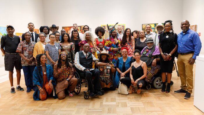 A group of people standing and sitting in a gallery space.