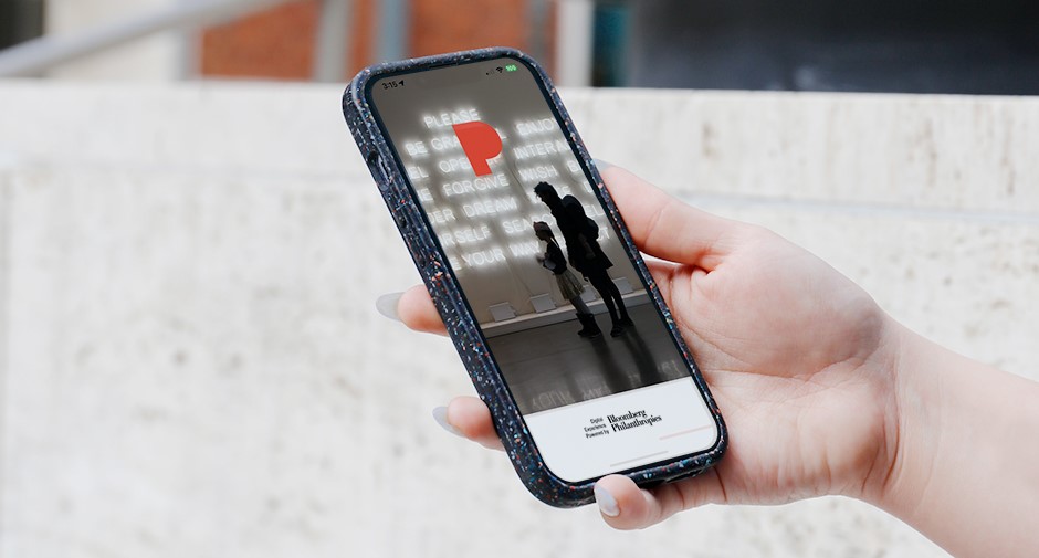 Hand holding a smartphone displaying the Bloomberg Connects app