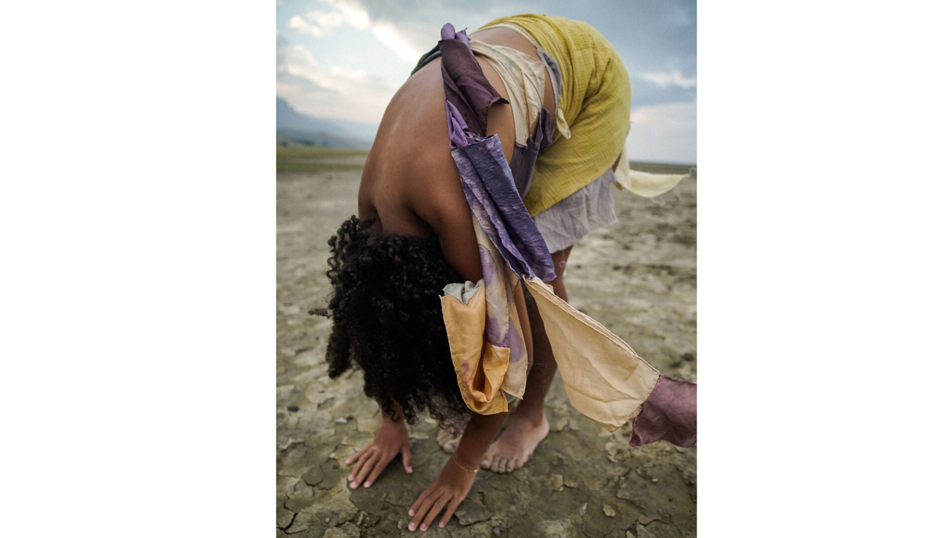Photo of a woman on a beach bending over in a forward fold.