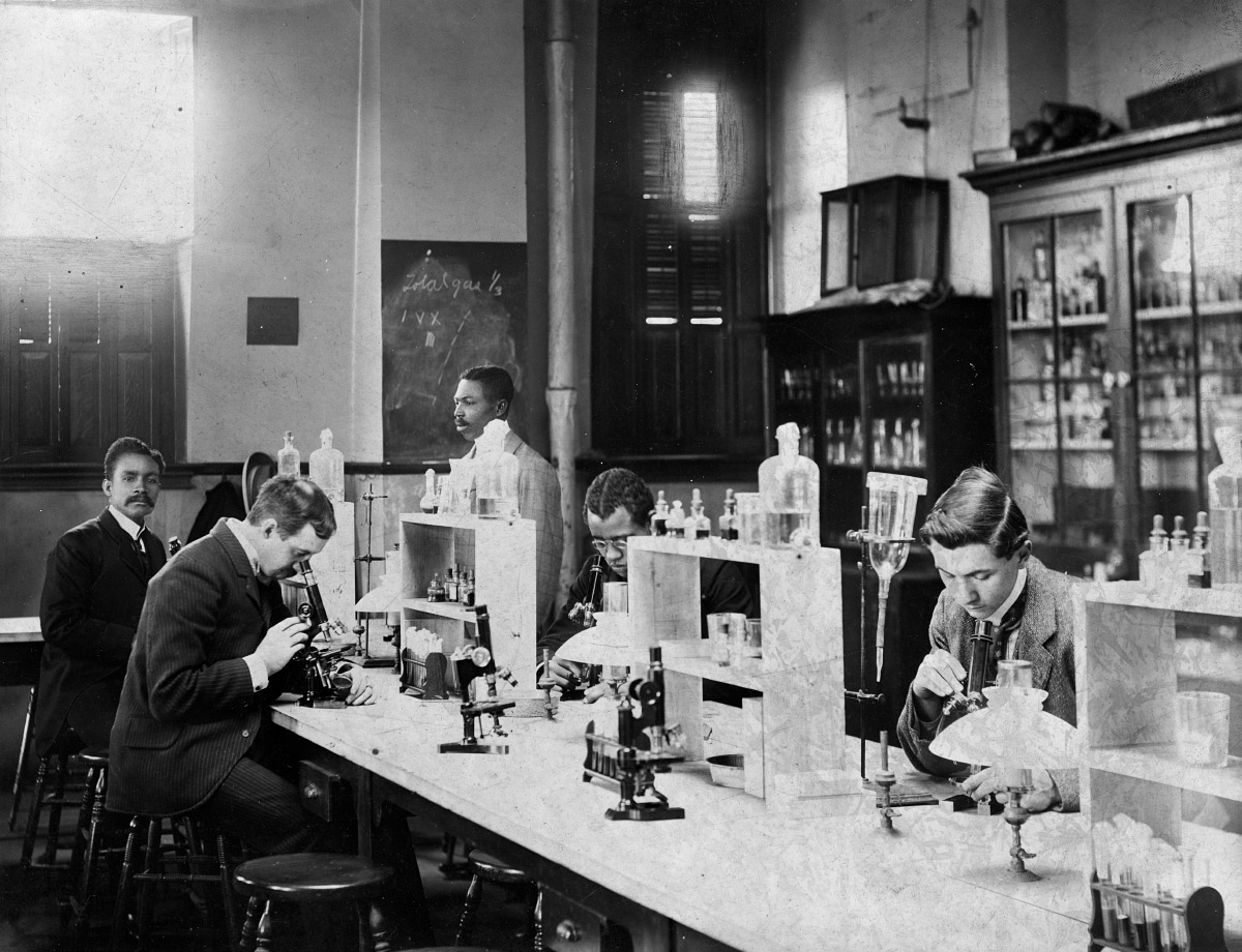 Old black and white photo of African American and white men with science equipment in a lab