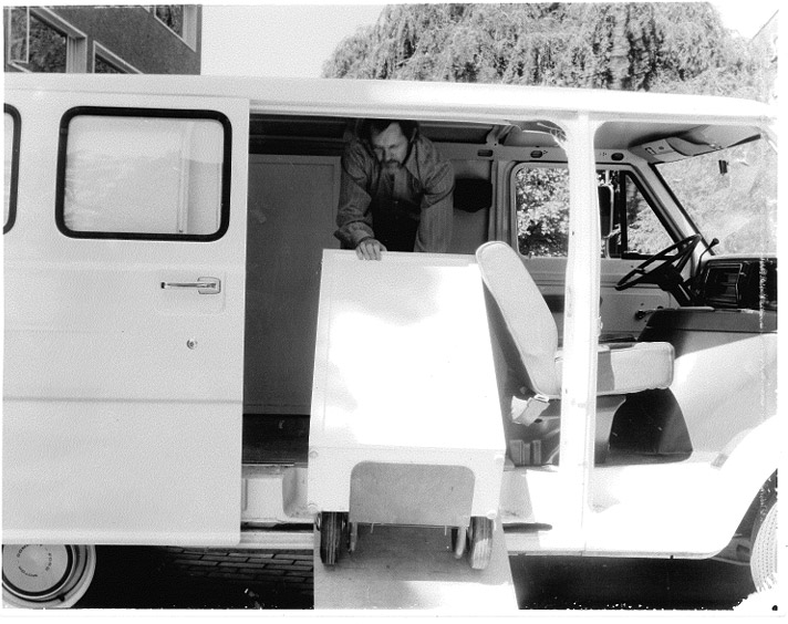 A person wheeling a cabinet up a ramp into a van.