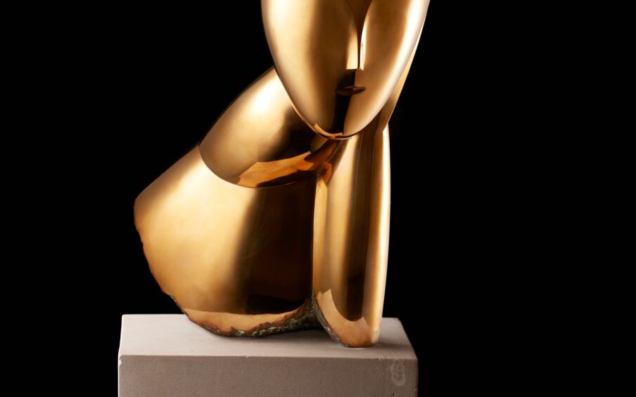 Image description: Muse, Constantin Brancusi, bronze on limestone base, 19 1/2 x 10 x 5 inches. A smooth, bronze, stylized bust of a woman’s head, elongated neck and shoulder. Front view: The woman’s egg-shaped head is smooth except for a raised V shape in the center representing the brow and finishing in a delicate nose. A small mouth is the only other feature on the face. Hair is suggested with rough, textured lines incised into the crown of the head. This texture appears darker than the glossy golden bronze face. A long neck extends from the head at left and is attached to a sloping shoulder. At right, the head seems to rest on a hand and forearm that extends to join the shoulder. The bottom edge of the sculpture has a rough and unfinished appearance. The bust rests on a gray cube of limestone that is juts a bit wider than the sculpture and about half as high. Left profile view: A smooth egg-shaped head smooth except for a small nose at the lower third of the profile. An simple C shaped ear is positioned below the textured hair. A gracefully shaped neck extends forward from a wedge-shaped shoulder. The bronze material folds back on itself, exposing rough edges, to rest on the base. Rear view: The textured hair appears to lengthen past the shoulder area ending in a blunt point. The sculpture’s shoulders fan out into a cone like structure that opens at an angle to expose the unpolished bronze inside. Right profile view: The hand and forearm shapes are visible from this view represented by simple elongated oval shape, a crease at the wrist giving definition to the two parts.