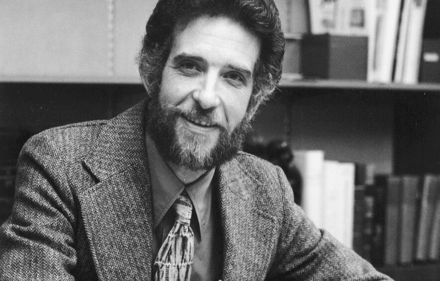 Black and white photo of a man with a beard wearing a suit and tie.