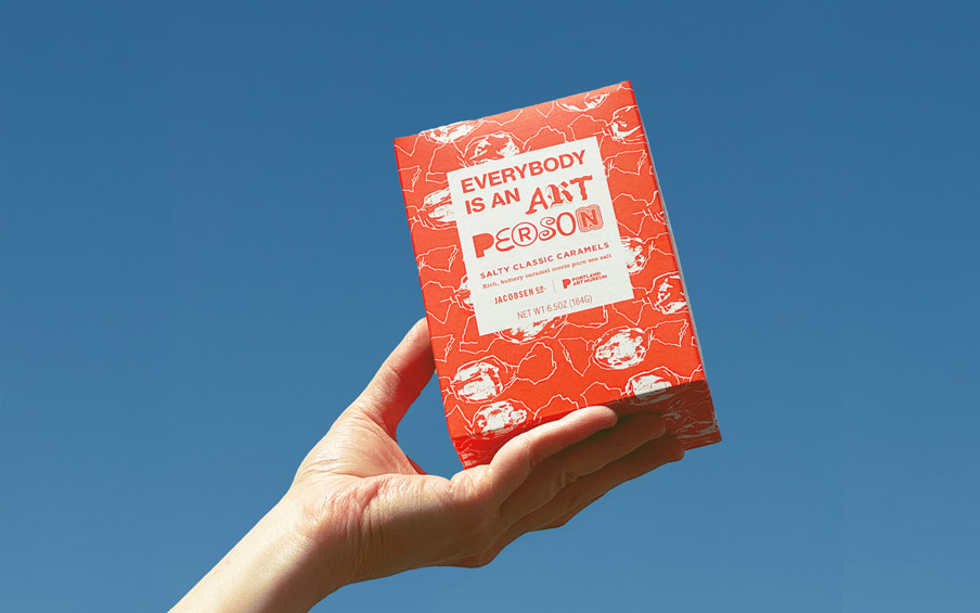 A hand holding a box of Jacobsen Sea Salt Caramels.