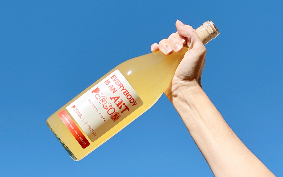 A hand holding a bottle of wine.