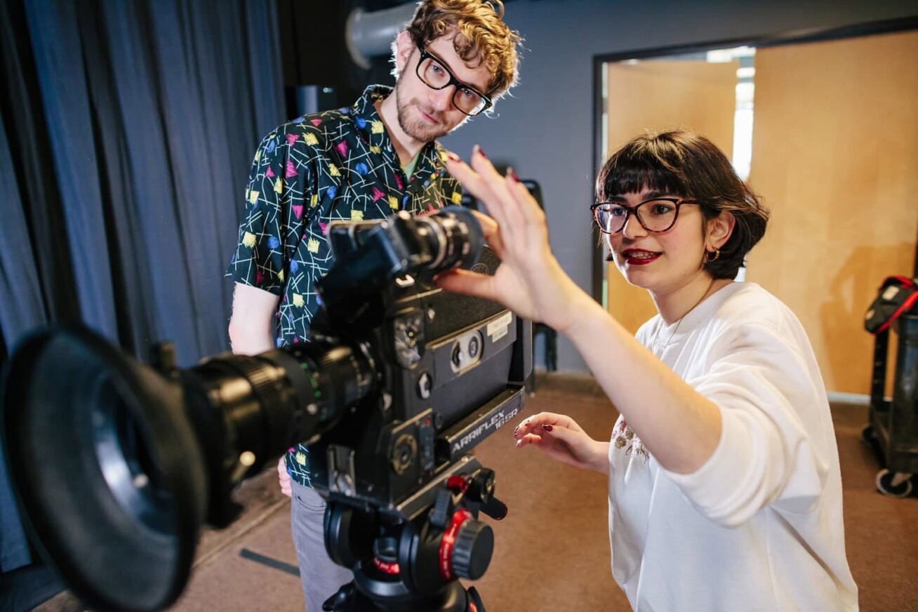 Two people operating a  film camera.