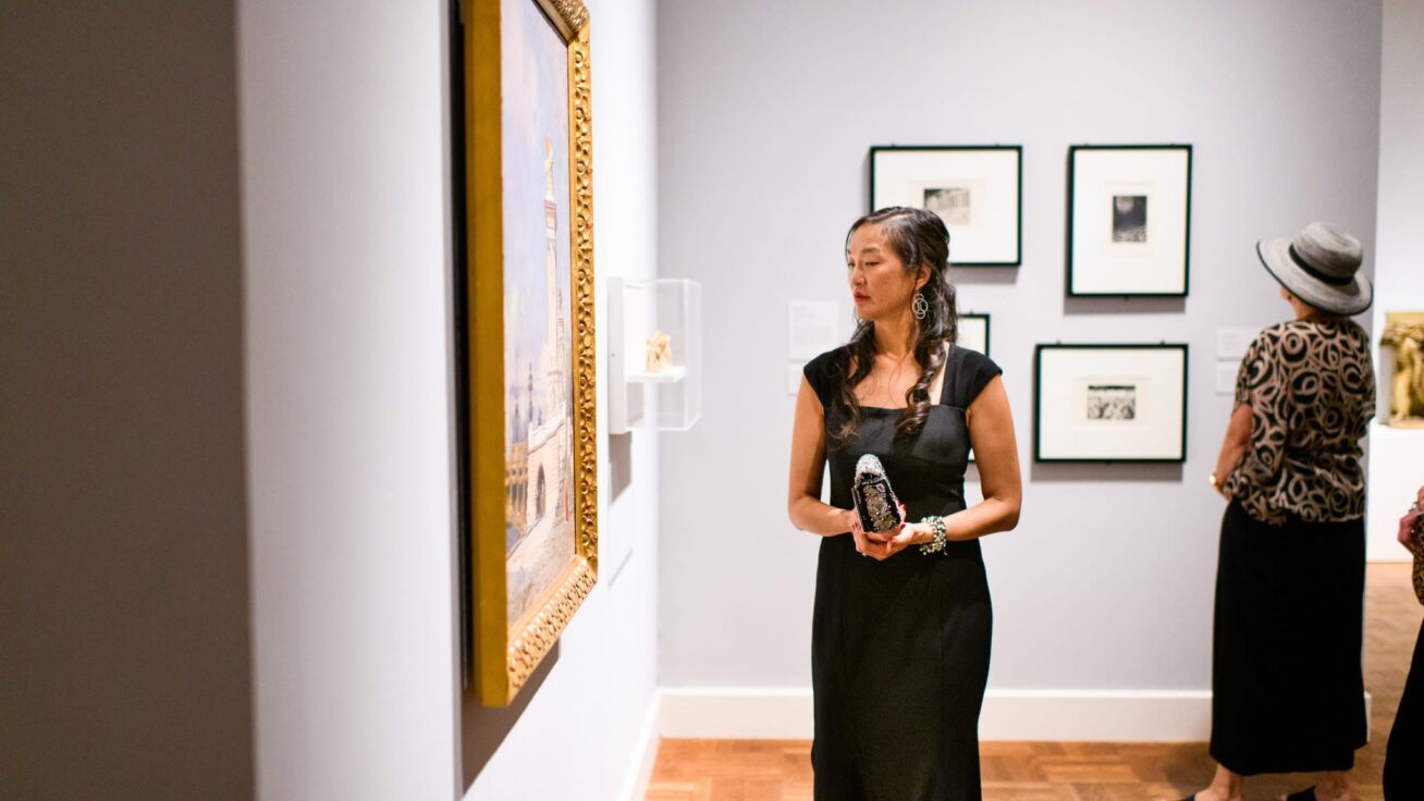 A person looking at framed art on a gallery wall.