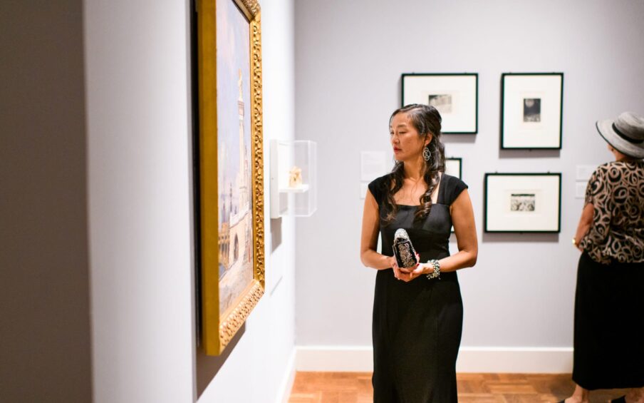 A person looking at framed art on a gallery wall.