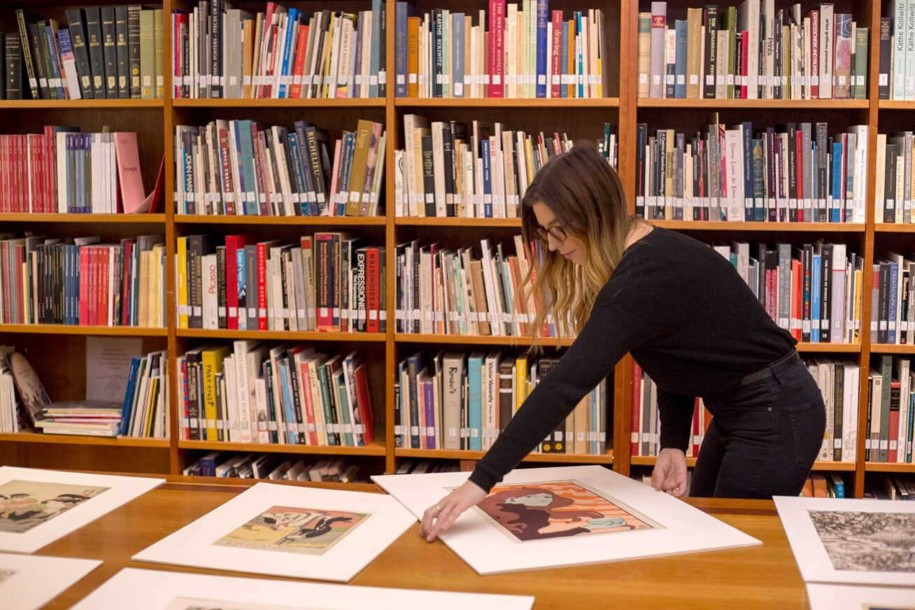 A person examining framed prints.