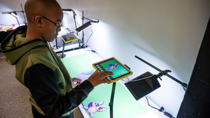 A boy with eyeglasses looking at an iPad mounted over a paper owl.