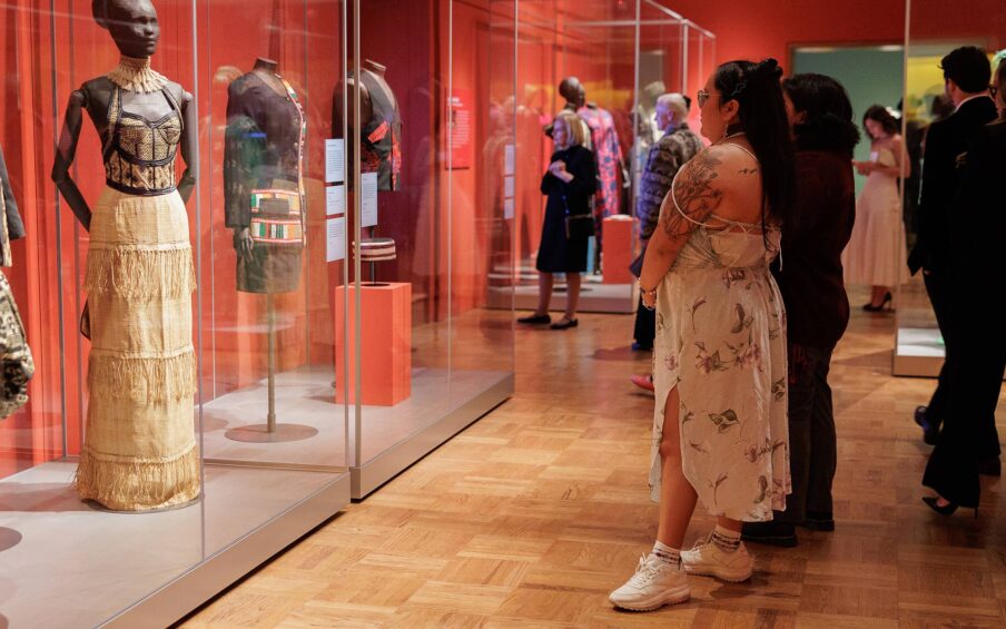 People viewing garments displayed in glass cases.