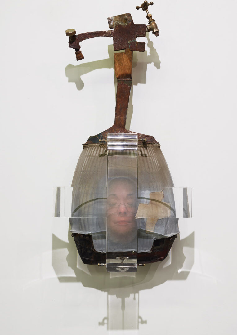 Sculpture made of metal, glass, and plastic with the image of a woman's face with closed eyes in the middle
