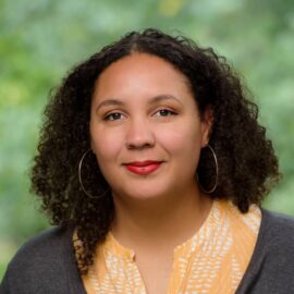 Headshot of a person with a green, leafy background.