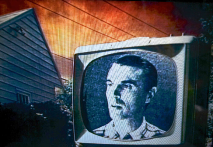 A music video film still with a black and white television with David Byrne's face on it