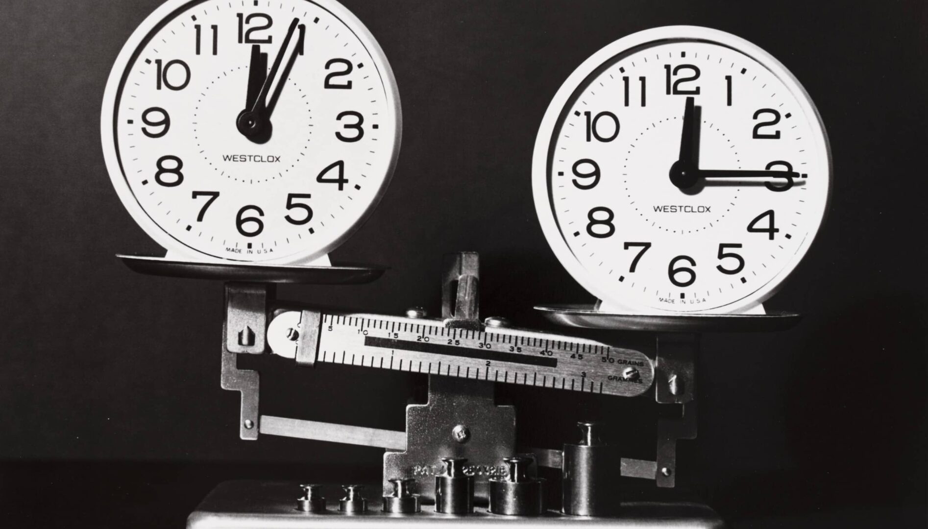 Two analog clocks sitting atop a balancing scale.