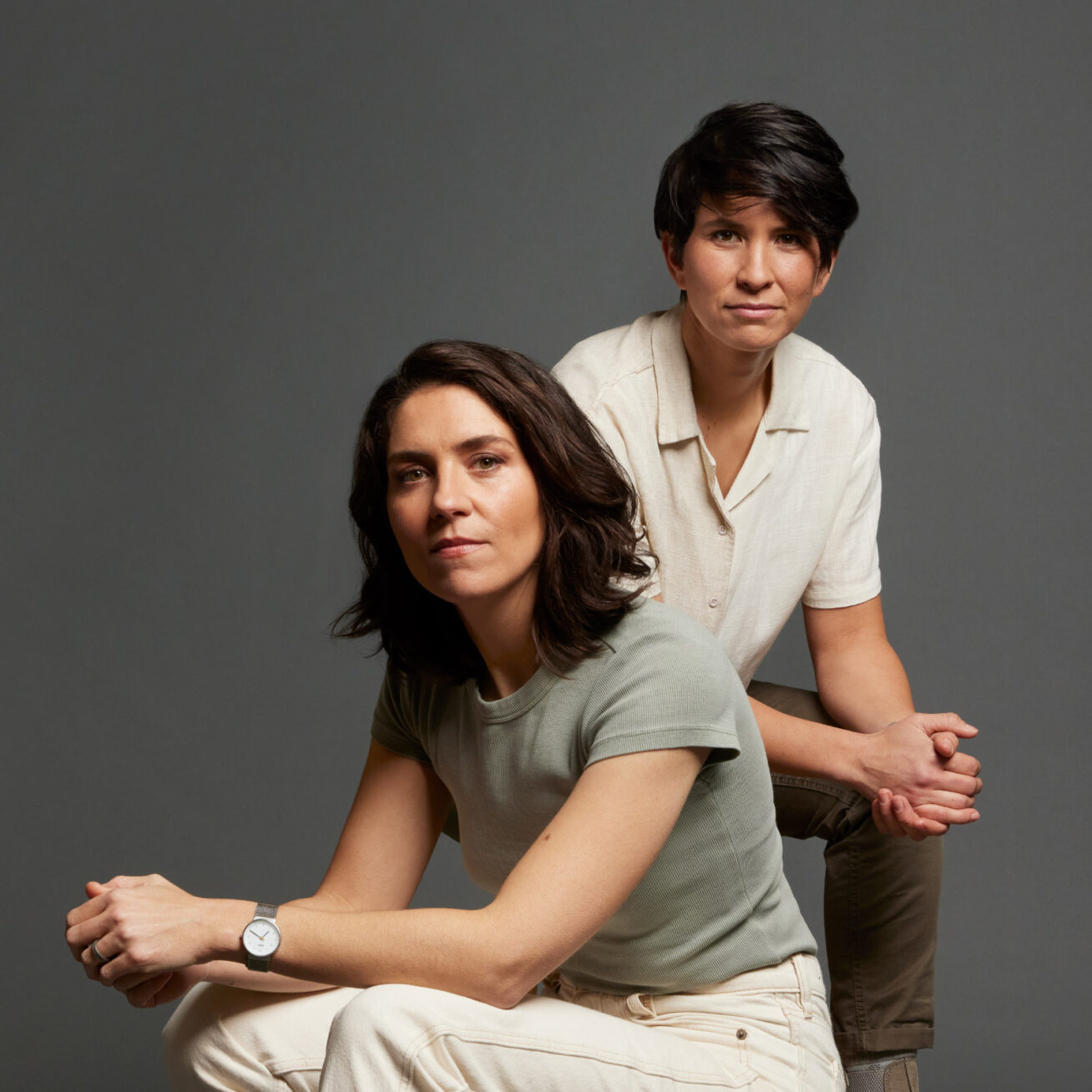 Two people posing in front of a gray backdrop.