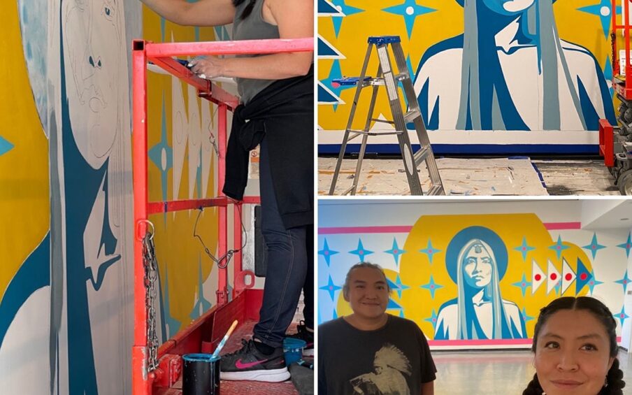 Image descriptions, clockwise from left: 1. A collage of three photos showing the artist Lynette Haozous and her assistant, Andrew Benally working on a mural. The first photo takes up the space on the left and features Haozous standing on a motorized lift painting the eye of a partially painted figure on the museum wall. Haozous stands on the red lift facing left, her right hand holding a brush touching the wall. Haozous is a Native American woman with dark hair swept back into two braids. She wears a gray sleeveless top and jeans with a dark shirt tied around her waist and black sneakers. A pot of blue paint sits at her feet. The mural taking shape on the wall portrays the head and shoulders of a larger-than-life figure with long hair in blue and gray. The figure is set against a bright yellow background with a halo-like shape around the head. Light blue four, pointed stars with white circle in their centers surround the figure. Two more photos are stacked on the right. 2. The top features the mural in progress with a table, ladder, and motorized lift in front of it. The mural’s central figure is the head and shoulders of a figure with long straight hair rendered in blues and grays. The figure gazes directly ahead, with facial features and clothing rendered in light blues on white. A darker blue halo is around the head within a much larger bright yellow organic cloud-like shape. Layered over this are light blue four-pointed stars in rows on either side of the figure. To the left of the figure, four dark blue, pyramid shaped triangles outlined in white are stacked on top of one another. The top and bottom triangles have large white dots in their centers and the middle two have red dots. To the right of the figure are four more pyramid shaped triangles, this time with red center dots and standing on their sides. The floor beneath the mural is covered with drop cloths. 3. The final photo at bottom right shows the artist and her assistant in the foreground with the completed mural in the background. Assistant Andrew Benally, a Native American man, stands at left, smiling. His hair is pulled back and he wears a black t-shirt with a figure in white wearing a feathered headdress. The artist Lynnette Haozous, stands at right, also smiling at the camera off to the right. She wears her hair back in braids, a plaid shirt and peach t-shirt. Behind them the mural is displayed next to a window with natural light.