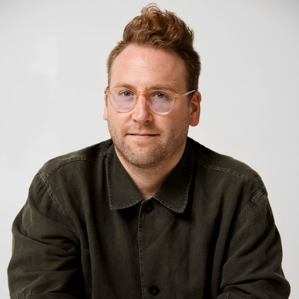 Photo of a man with clear eyeglasses and a dark button down shirt.