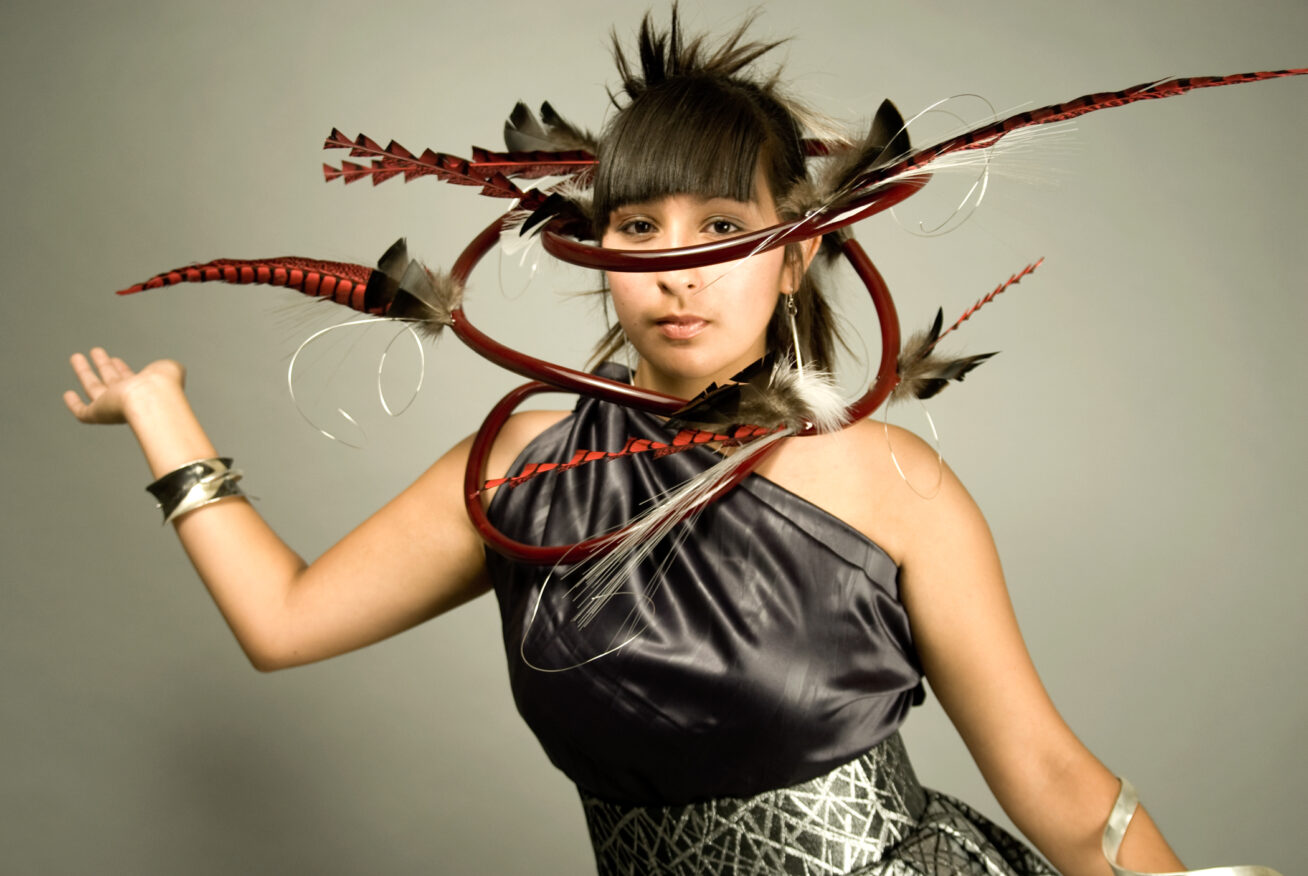 Photograph of a Native woman wearing an elaborate boa/headpiece made of metal and feathers