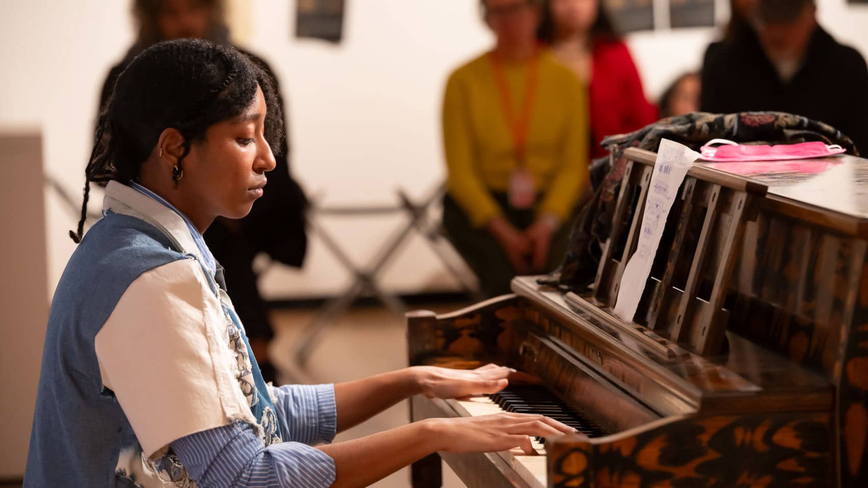 A person playing piano before a small audience.