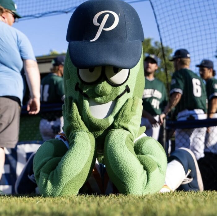 Photo of the Portland Pickles baseball team mascot, Dillon T Pickles, in a green pickle costume and a blue baseball hat with a P on it.