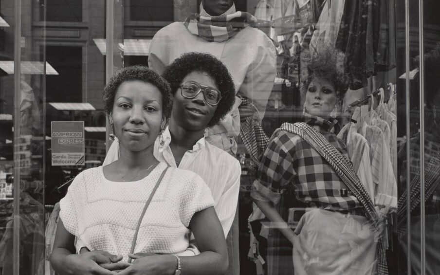 Black and white photograph of a couple standing in front of a shop window.