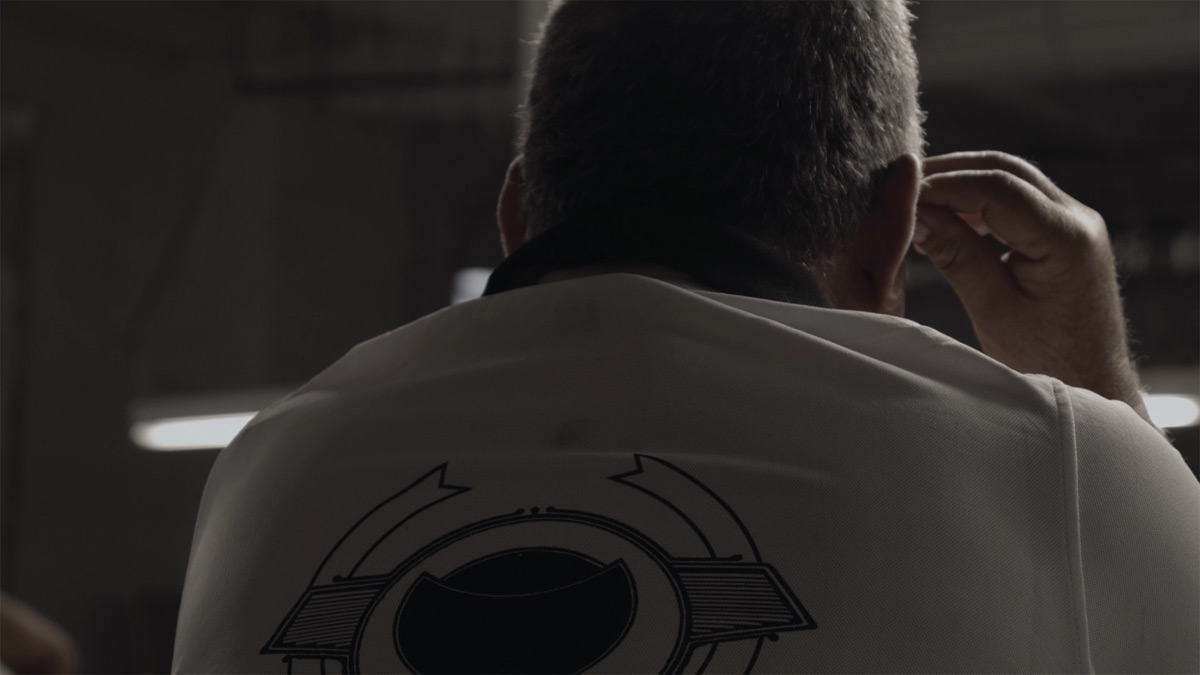 Black and white film still of the back of someone's head and the top of their back