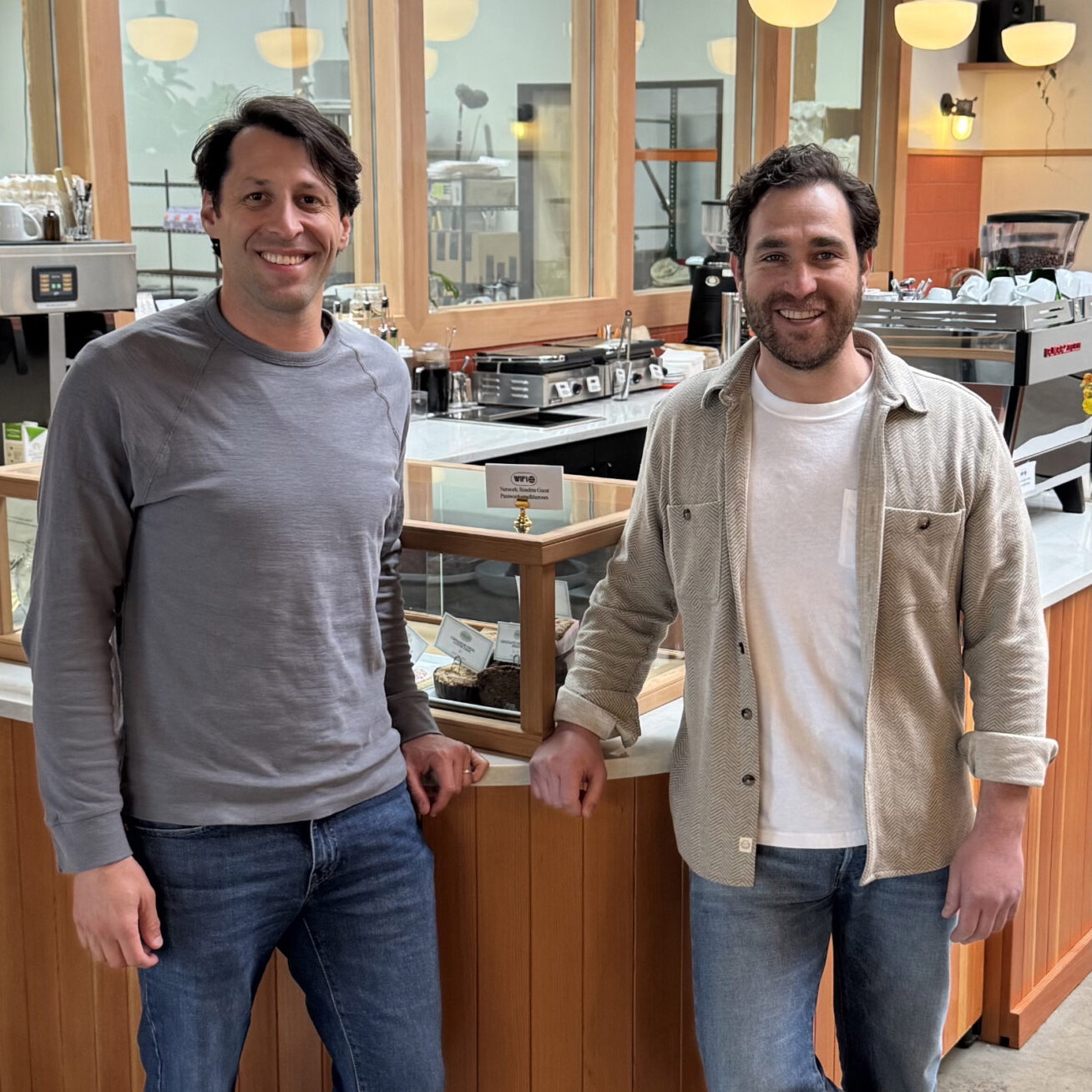Two people standing in front of a counter in a coffee shop.
