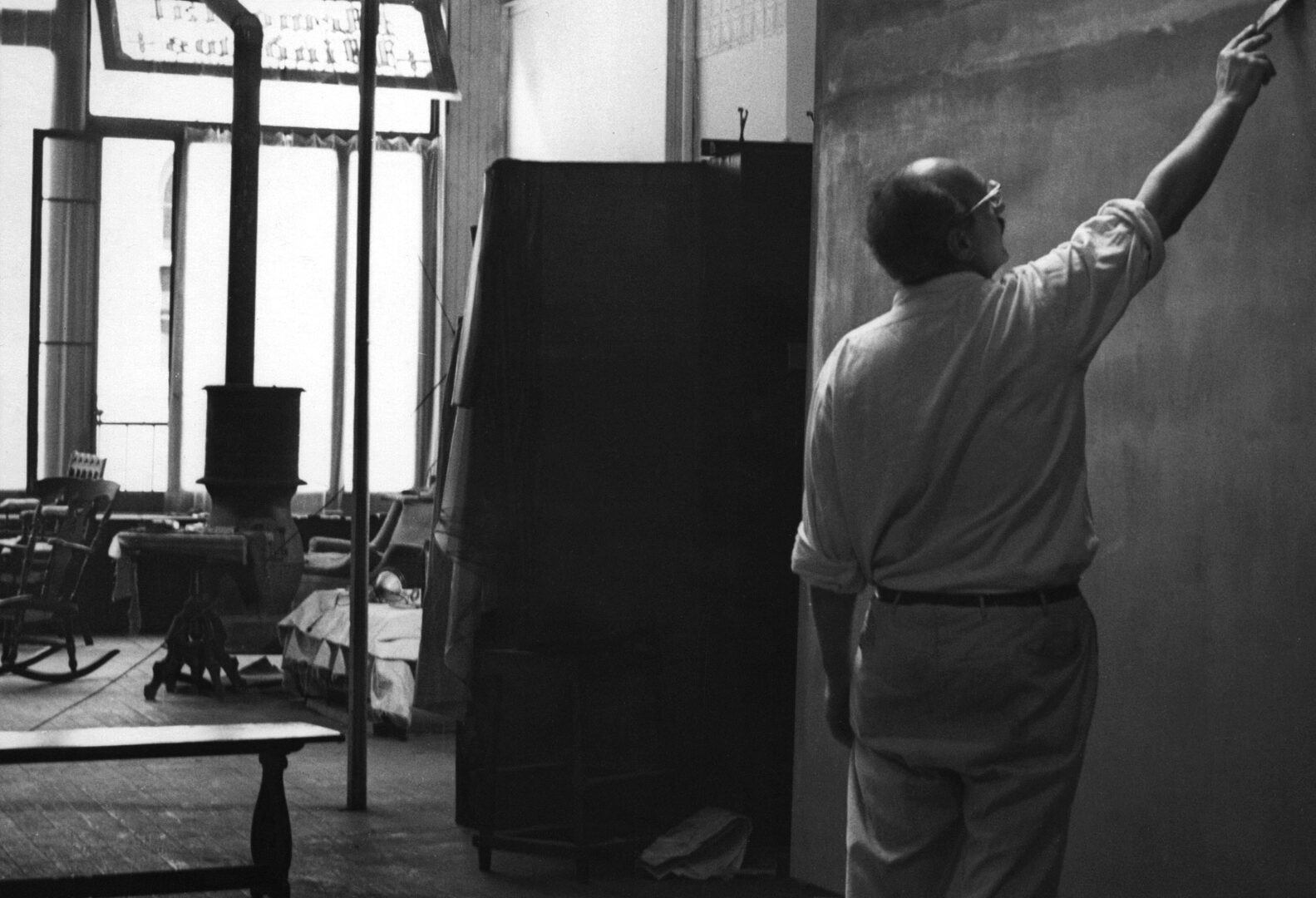 A person painting on a large canvas in a studio.