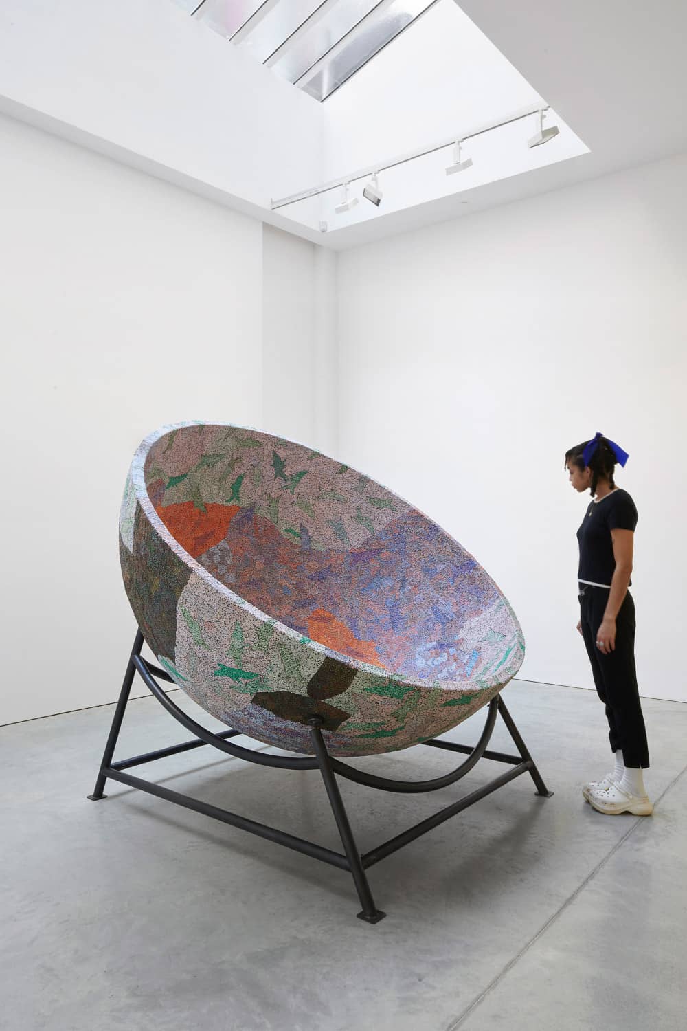 A person standing next to a large bowl-shaped sculpture.