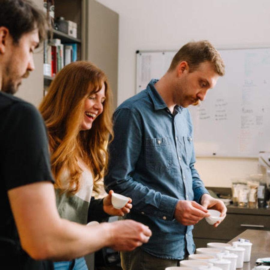 Three people standing next to a table with tea cups.