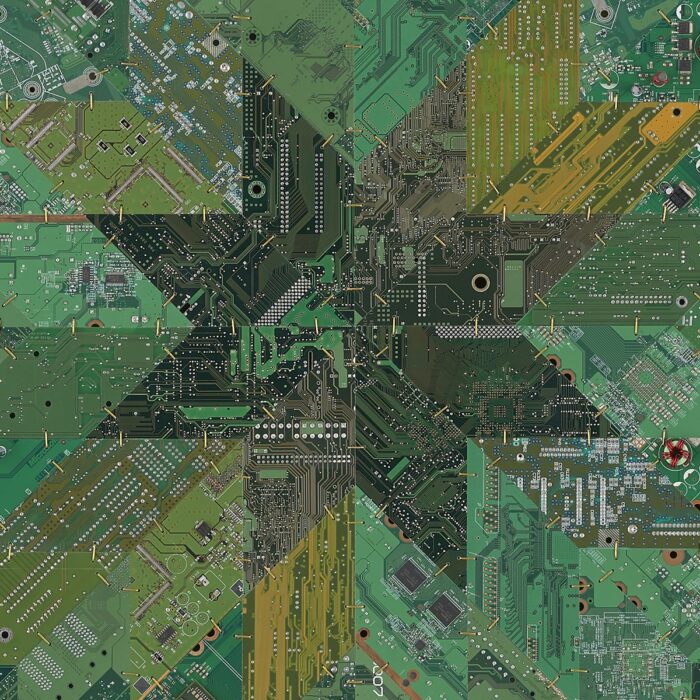 A large square work composed of circuit boards in various shades of green pieced together like a quilt and connected with brass wire.