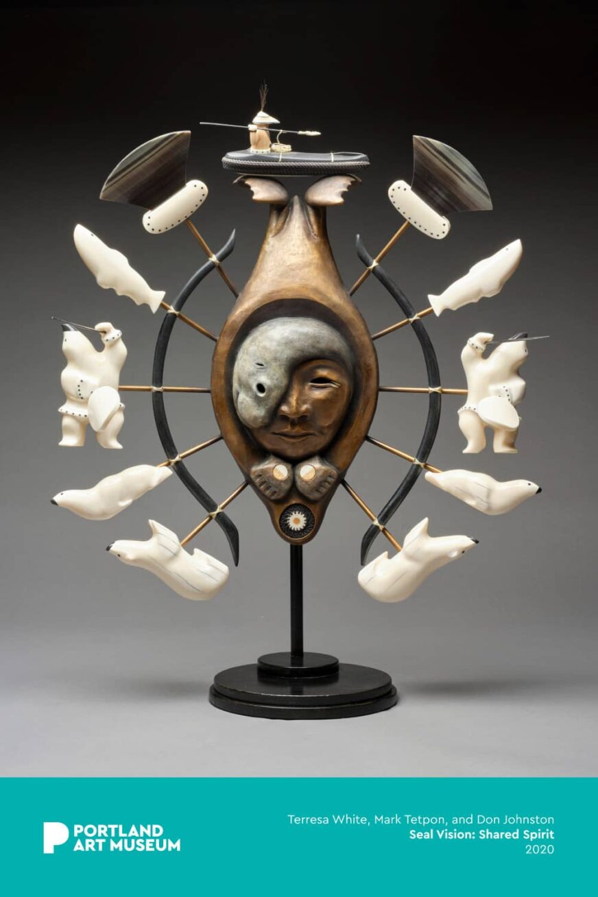 Sculpture of a masked face surrounded by polar bears, seals, and a person in a boat.