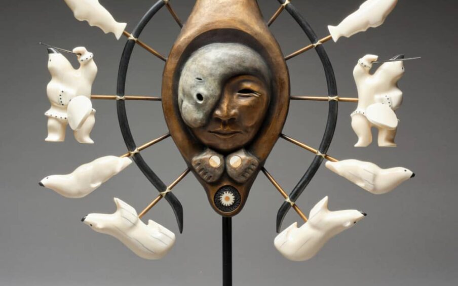Sculpture of a masked face surrounded by polar bears, seals, and a person in a boat.